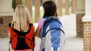 Two young girls carrying their book bags