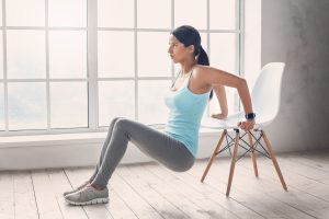 Woman exercising at home with chair.